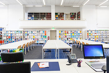 Lesesaal 1 Campus Treskowallee. Blick von der Theke aus mit Bildschirmarbeitsplatz im Vordergrund.