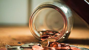 Open glass jar with coins coming out of it. Image under licence Unsplash